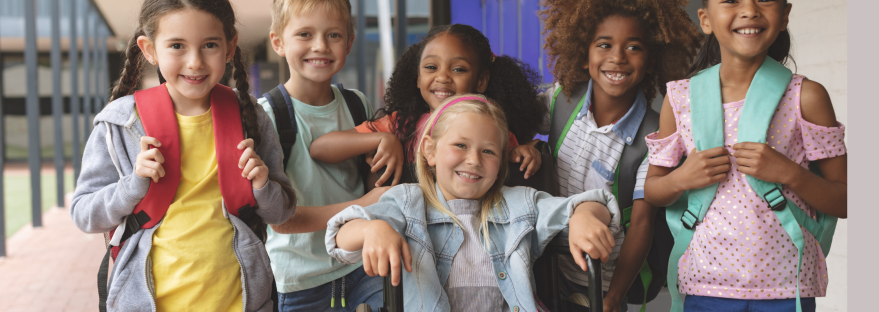 A group of children looking at the camera, one in a wheel chair